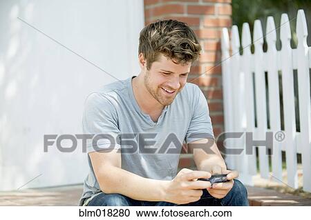 Stock Image - Man using cell phone outdoors. Fotosearch