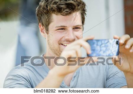 Stock Image - Man using cell phone outdoors. Fotosearch