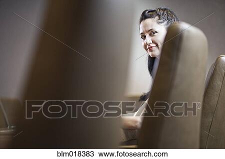 Stock Image - Mixed race businesswoman sitting at meeting table. Fotosearch