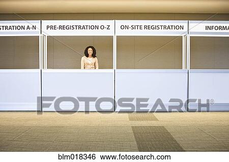 Stock Photograph - Mixed race businesswoman smiling in registration booth. Fotosearch