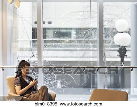 Stock Photography - Mixed race businesswoman using cell phone. Fotosearch