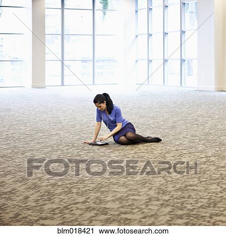 Stock Image - Mixed race businesswoman using tablet computer in empty room. Fotosearch