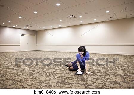 Stock Photography - Mixed race businesswoman using tablet computer in empty room. Fotosearch