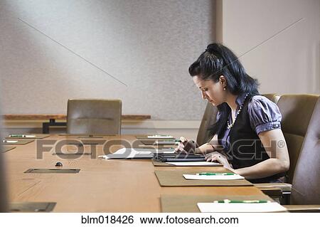 Stock Photograph - Mixed race businesswoman working at meeting table. Fotosearch