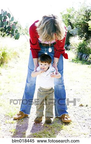 Mother helping toddler son walk outdoors View Large Photo Image Stock Photography - Mother helping toddler son walk outdoors. Fotosearch