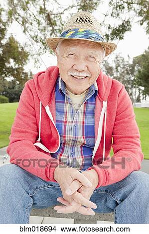 Picture - Older Asian man smiling outdoors. Fotosearch