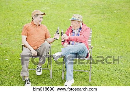 Stock Image - Older men drinking beer outdoors. Fotosearch