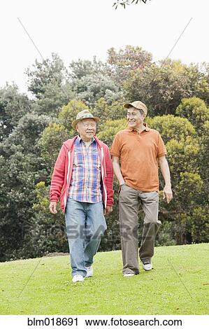 Stock Image - Older men walking together outdoors. Fotosearch
