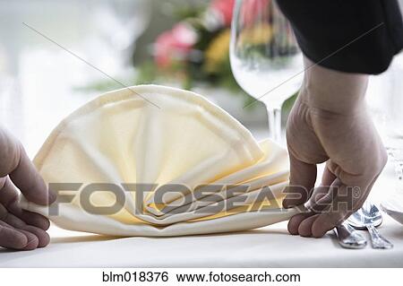 Stock Photograph - Pacific Islander waiter setting table in dining room. Fotosearch
