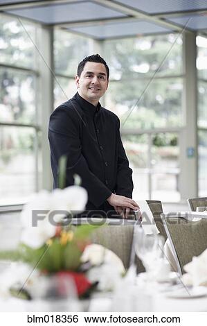 Stock Photograph - Pacific Islander waiter smiling in dining room. Fotosearch