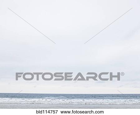Stock Photo - Beach and ocean under overcast sky. Fotosearch