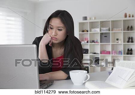 Bored mixed race businesswoman using laptop View Large Photo Image Stock Photo - Bored mixed race businesswoman using laptop. Fotosearch