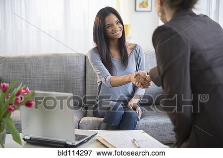 Businesswomen shaking hands in living room View Large Photo Image Stock Photo - Businesswomen shaking hands in living room. Fotosearch