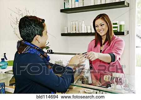 Cashier serving client in salon View Large Photo Image Picture - Cashier serving client in salon. Fotosearch