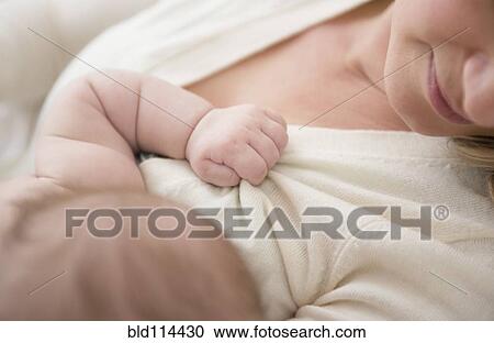 Stock Image - Caucasian baby gripping mother's sweater. Fotosearch