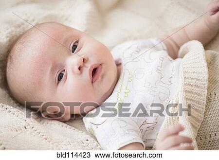 Stock Image - Caucasian baby laying on bed. Fotosearch