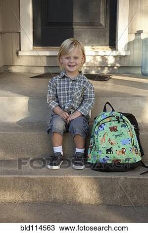 Stock Image - Caucasian boy with backpack on front steps. Fotosearch