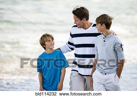 Caucasian father and sons walking on beach View Large Photo Image Stock Image - Caucasian father and sons walking on beach. Fotosearch