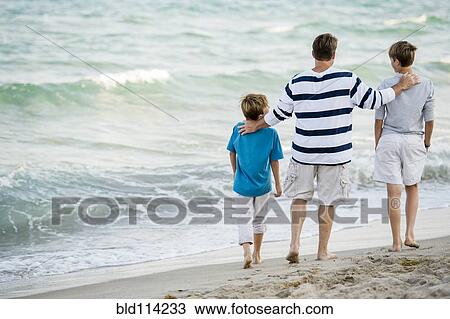Caucasian father and sons walking on beach View Large Photo Image Stock Image - Caucasian father and sons walking on beach. Fotosearch