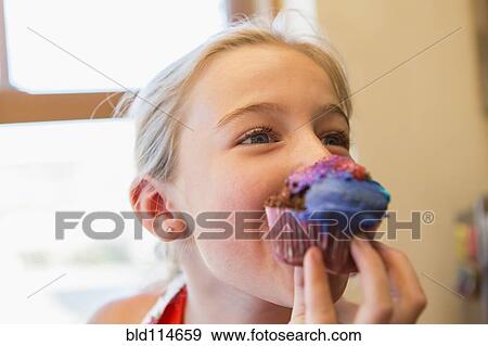 Stock Photo - Caucasian girl eating cupcake. Fotosearch