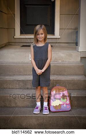 Stock Image - Caucasian girl with backpack on front steps. Fotosearch