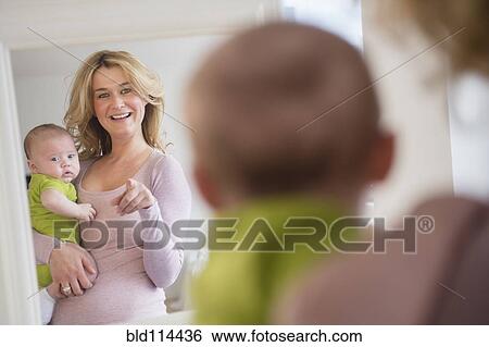 Stock Photograph - Caucasian mother and baby admiring themselves in mirror. Fotosearch