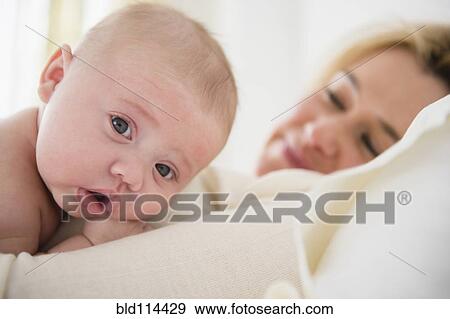 Stock Photo - Caucasian mother and baby laying on bed. Fotosearch