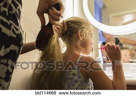 Stock Photo - Caucasian mother brushing daughter's hair. Fotosearch