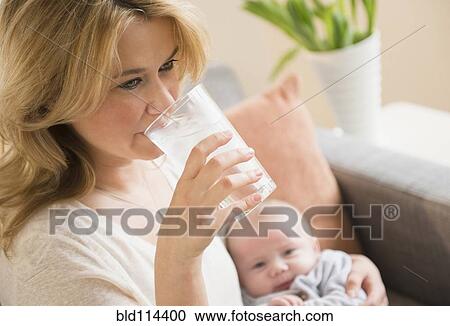 Stock Image - Caucasian mother drinking glass of water. Fotosearch