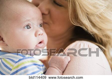 Stock Photo - Caucasian mother kissing baby. Fotosearch