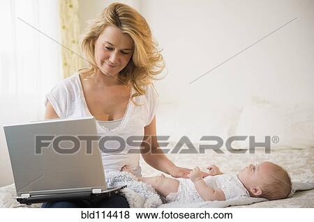 Stock Photo - Caucasian mother with baby using laptop. Fotosearch