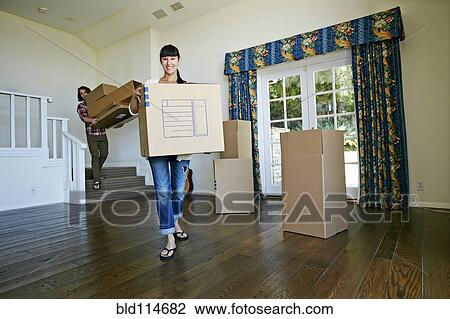 Couple carrying boxes in new home View Large Photo Image Stock Image - Couple carrying boxes in new home. Fotosearch