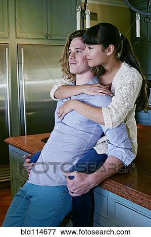Stock Photo - Couple hugging in kitchen. Fotosearch