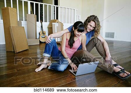 Stock Photo - Couple using laptop in new home. Fotosearch