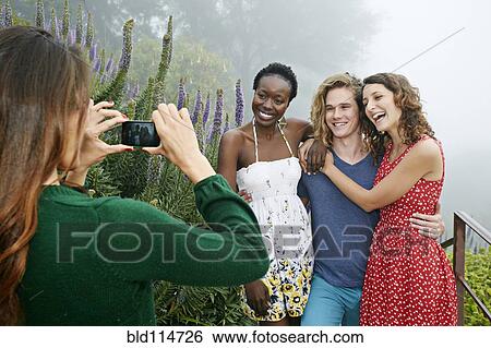 Stock Photograph - Friends taking pictures together outdoors. Fotosearch