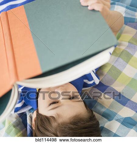 Stock Photo - Hispanic boy reading on bed. Fotosearch