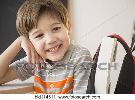 Stock Image - Hispanic boy smiling at desk. Fotosearch