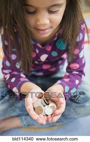 Stock Image - Hispanic girl holding handful of coins. Fotosearch