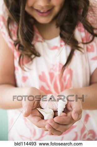 Stock Image - Hispanic girl holding seashells. Fotosearch
