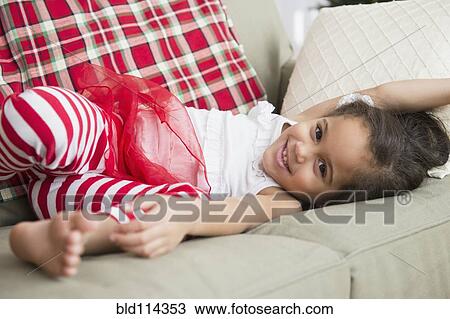 Stock Image - Hispanic girl laying on sofa. Fotosearch