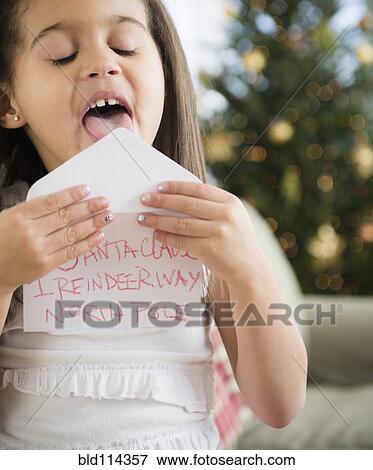 Stock Photo - Hispanic girl sealing envelope for Santa. Fotosearch