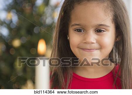 Picture - Hispanic girl smiling by lit candle. Fotosearch