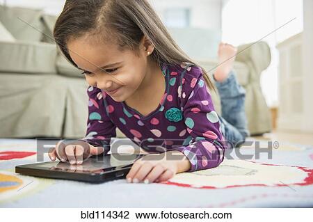 Stock Image - Hispanic girl using tablet computer. Fotosearch