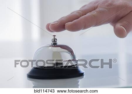 Stock Image - Hispanic man ringing service bell on desk. Fotosearch