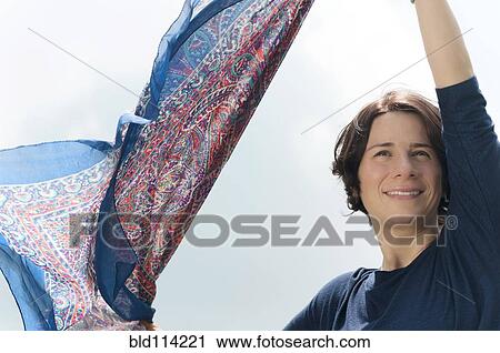 Stock Image - Hispanic woman playing with scarf outdoors. Fotosearch