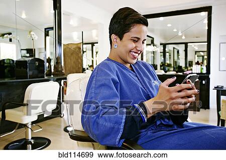 Hispanic woman using cell phone in salon View Large Photo Image Stock Photo - Hispanic woman using cell phone in salon. Fotosearch