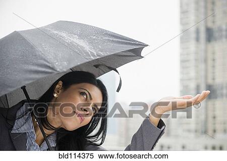 Indian businesswoman feeling rain from under umbrella View Large Photo Image Stock Photography - Indian businesswoman feeling rain from under umbrella. Fotosearch