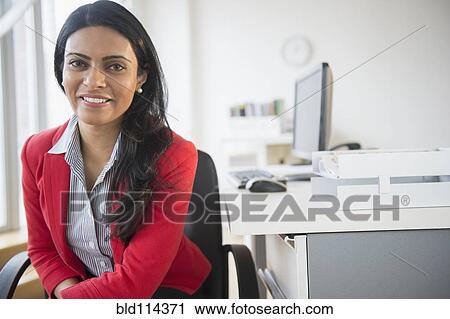 Stock Image - Indian businesswoman smiling at desk. Fotosearch