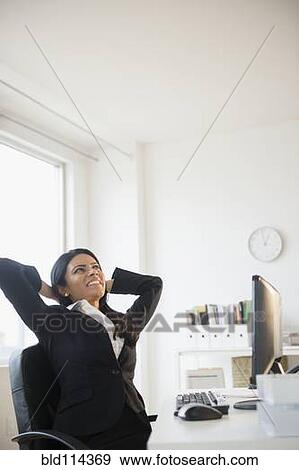 Indian businesswoman stretching at desk View Large Photo Image Stock Photo - Indian businesswoman stretching at desk. Fotosearch