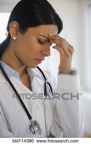 Indian doctor rubbing her forehead View Large Photo Image Stock Image - Indian doctor rubbing her forehead. Fotosearch